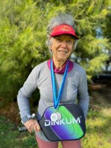 Lady holding pickleball racquet wearing red hat