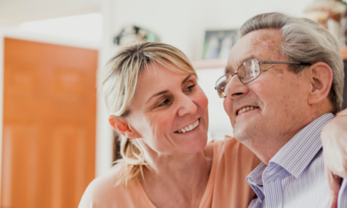 Elderly man photographed smiling with loved one.