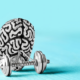 Metallic brain with hand weights on blue background for brain pacemaker Parkinson's article.